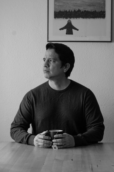 Carlos Alberto mirando a un lado y sostiene una taza de te